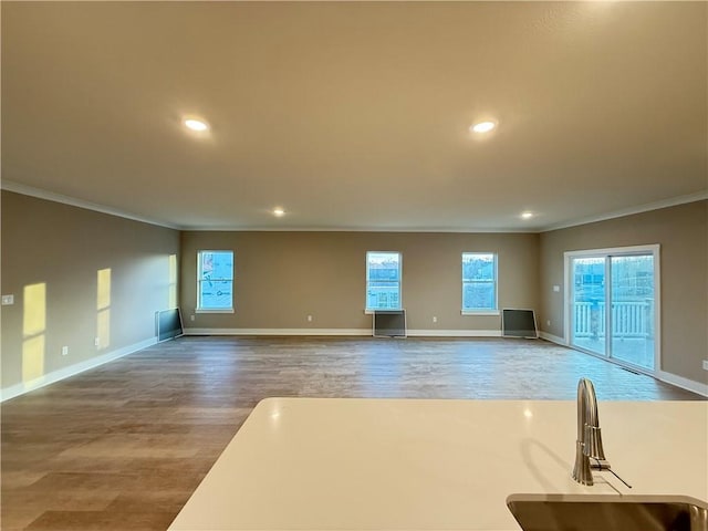 unfurnished living room with baseboards, ornamental molding, wood finished floors, and recessed lighting