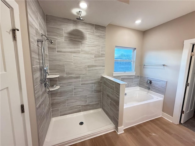 full bath with tiled shower, a bath, and wood finished floors