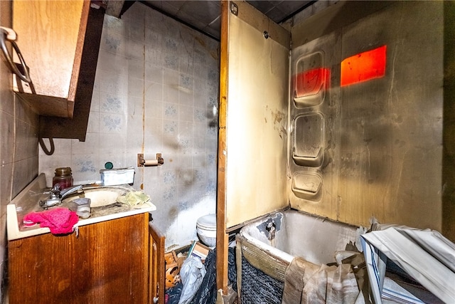 bathroom featuring vanity, tile walls, a bathtub, and toilet