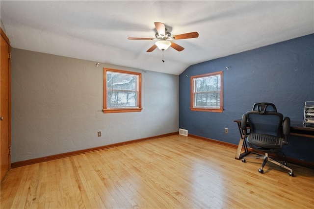 unfurnished office with ceiling fan, vaulted ceiling, a wealth of natural light, and light hardwood / wood-style flooring