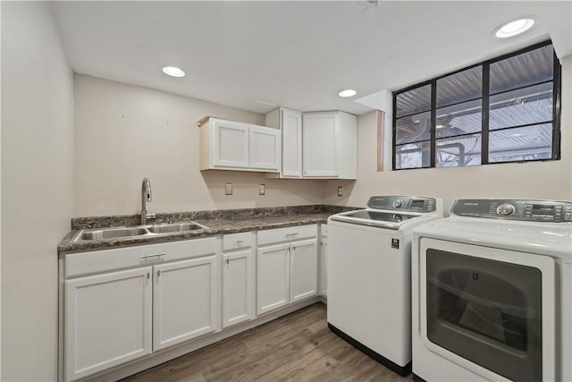 washroom with washing machine and clothes dryer, wood-type flooring, cabinets, and sink