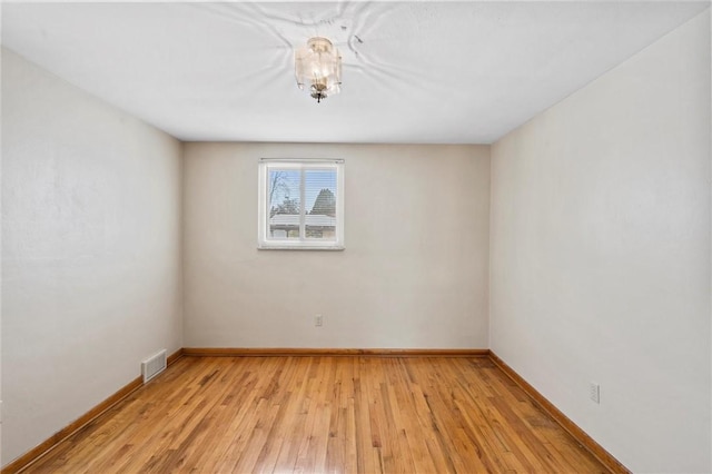 spare room with light wood finished floors, visible vents, and baseboards