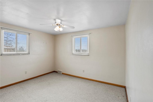 carpeted empty room with baseboards, visible vents, and ceiling fan