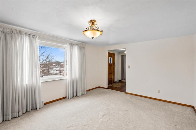 spare room with baseboards and light colored carpet