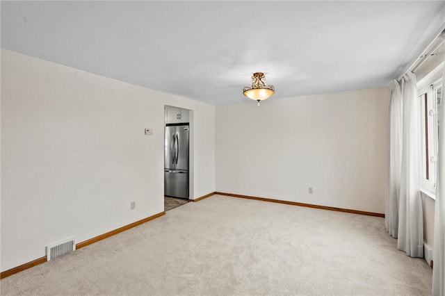 spare room with light carpet, visible vents, and baseboards