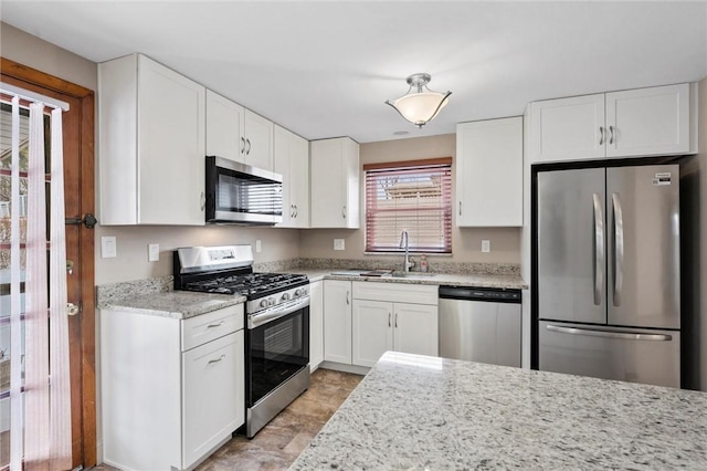 kitchen with light stone counters, sink, white cabinetry, and stainless steel appliances