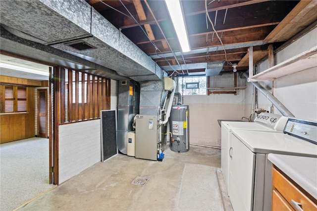 basement featuring washing machine and clothes dryer, visible vents, gas water heater, heating unit, and concrete block wall