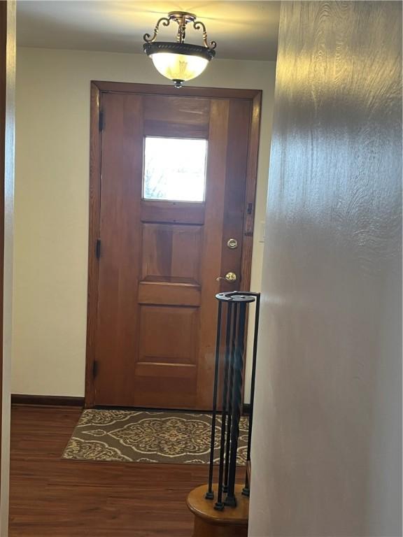 doorway featuring baseboards and wood finished floors