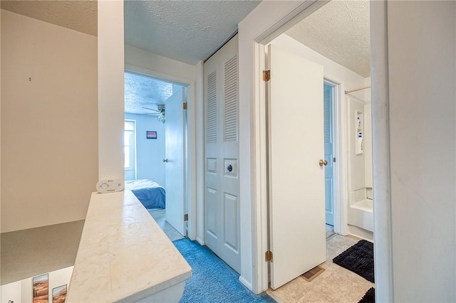 hallway featuring light carpet and a textured ceiling