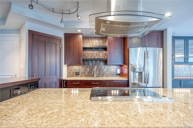 kitchen featuring light stone countertops, sink, tasteful backsplash, stainless steel fridge, and track lighting