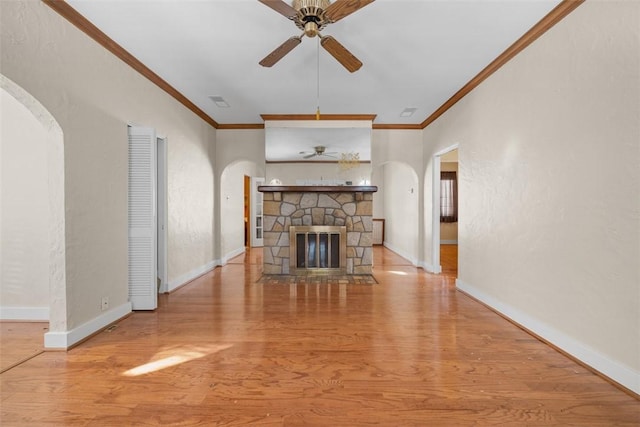 unfurnished living room featuring a fireplace, light wood-type flooring, ceiling fan, and ornamental molding