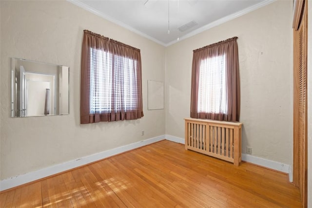 unfurnished room featuring wood-type flooring, crown molding, and a wealth of natural light