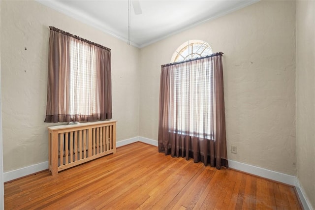 spare room featuring plenty of natural light, ceiling fan, wood-type flooring, and ornamental molding