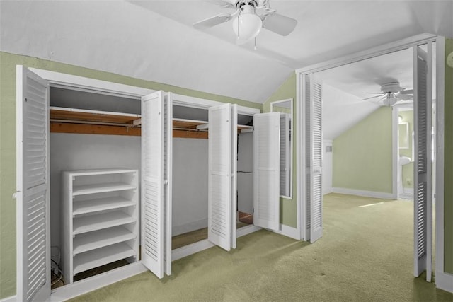 unfurnished bedroom featuring multiple closets, ceiling fan, carpet floors, and vaulted ceiling