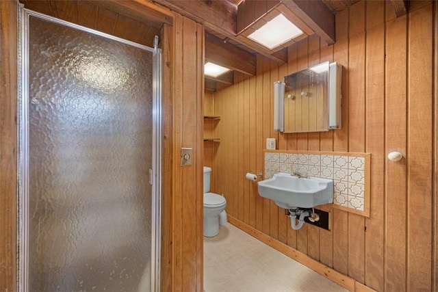 bathroom with wood walls, sink, a shower with shower door, and toilet