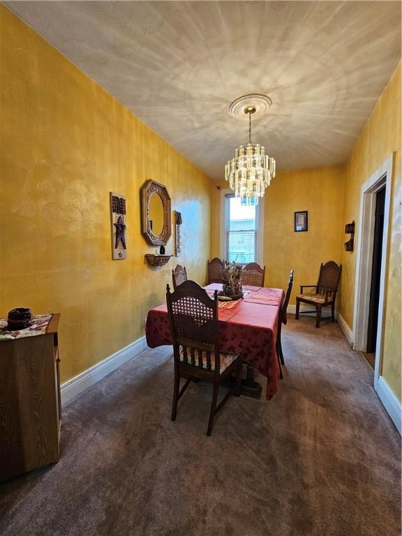 dining space featuring dark colored carpet and an inviting chandelier