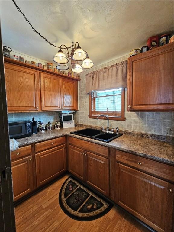 kitchen with decorative backsplash, dark stone countertops, sink, and light hardwood / wood-style flooring