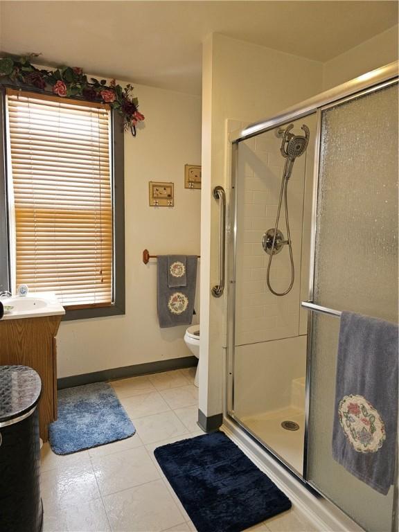 bathroom featuring tile patterned floors, vanity, an enclosed shower, and toilet