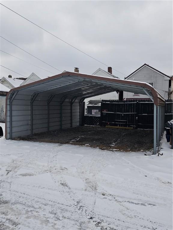 snow covered parking with a carport