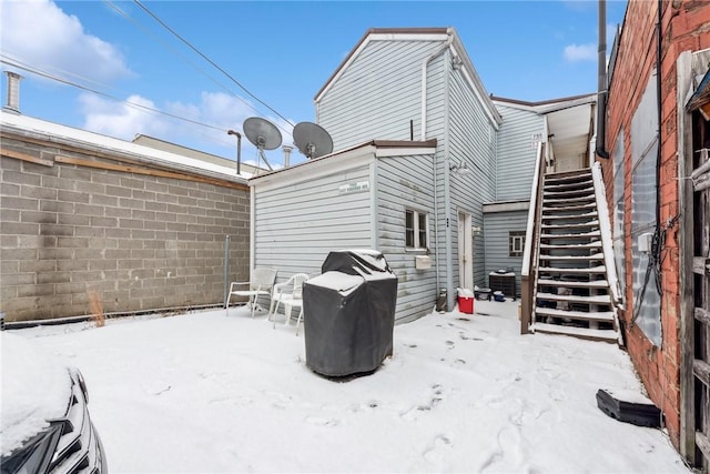 snow covered back of property featuring cooling unit