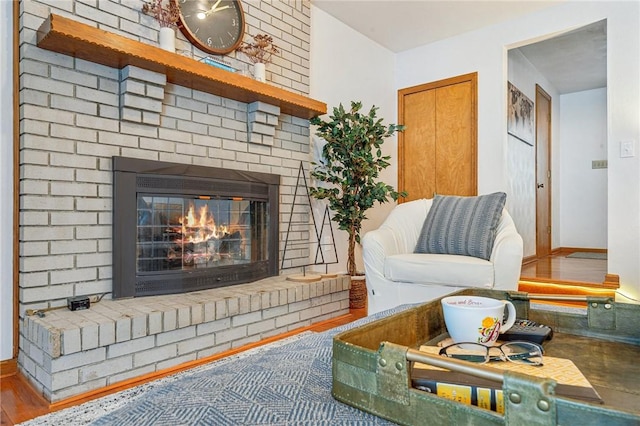 living room featuring a brick fireplace and wood-type flooring