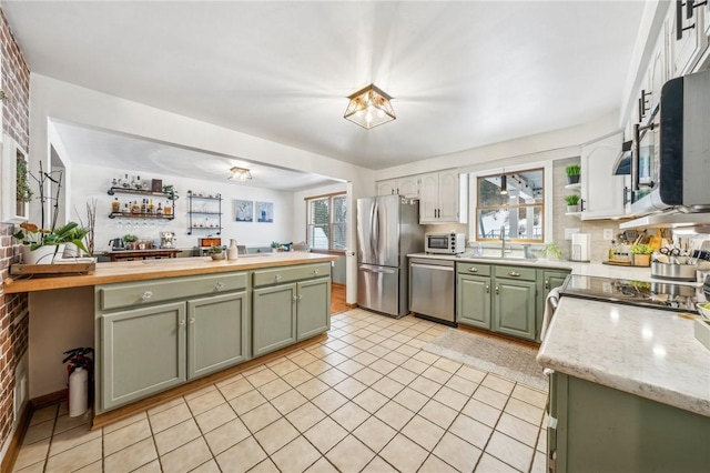 kitchen with sink, green cabinets, light tile patterned floors, and appliances with stainless steel finishes