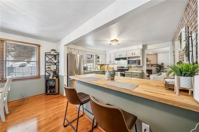 kitchen featuring kitchen peninsula, white cabinetry, appliances with stainless steel finishes, a kitchen breakfast bar, and sink