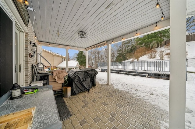 snow covered patio featuring a grill