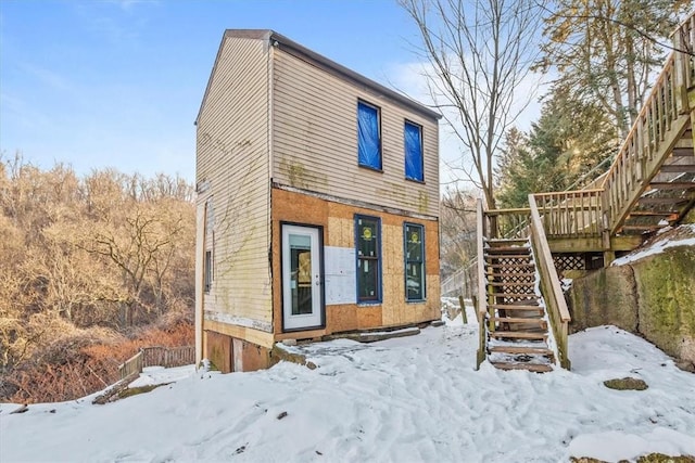 snow covered house featuring a wooden deck