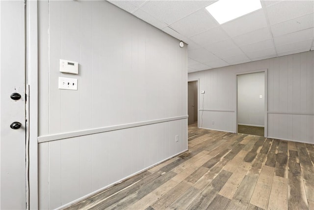 spare room with a paneled ceiling, wood walls, and hardwood / wood-style flooring