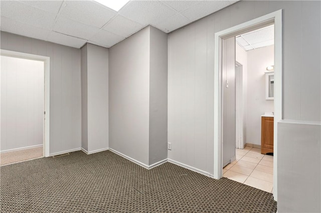 carpeted empty room featuring a paneled ceiling