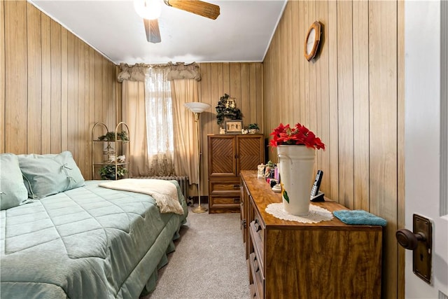 bedroom with ceiling fan, light colored carpet, and wooden walls