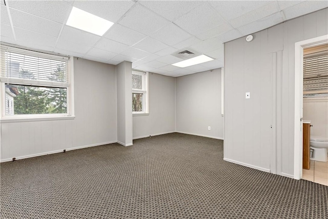 basement featuring dark carpet and a drop ceiling