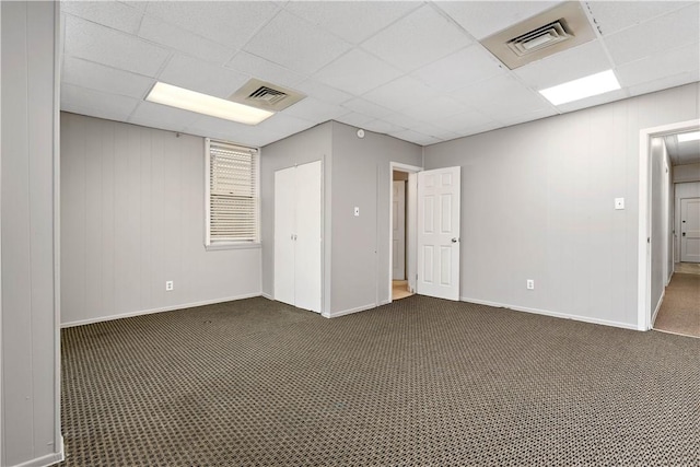 carpeted spare room featuring a drop ceiling