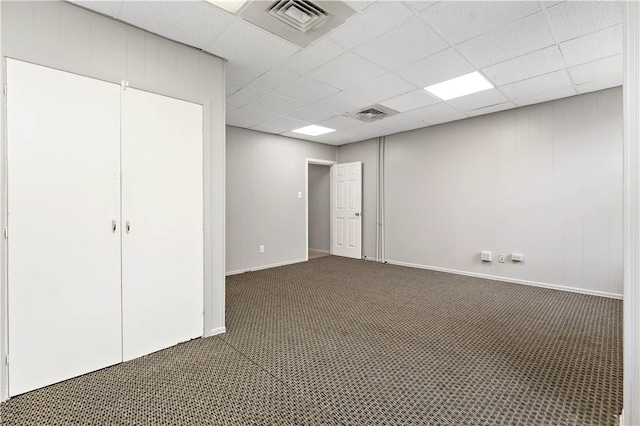 interior space with a paneled ceiling and dark carpet