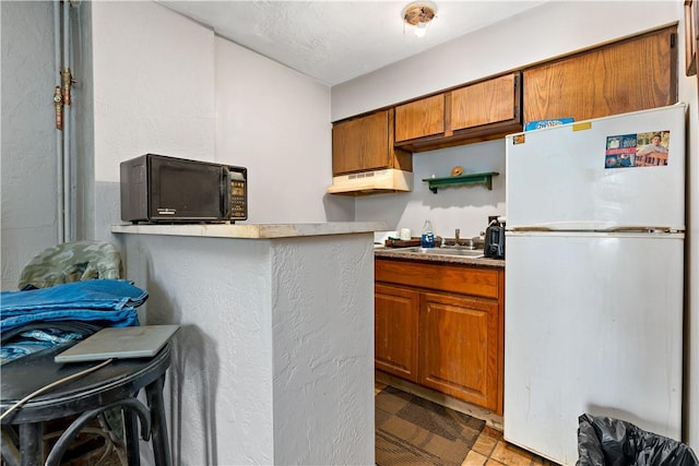 kitchen featuring white fridge, a breakfast bar area, and sink