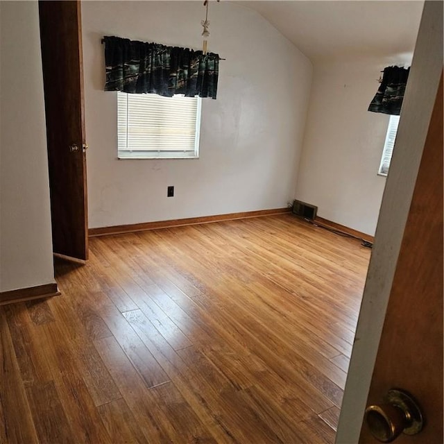 unfurnished room featuring hardwood / wood-style flooring and lofted ceiling