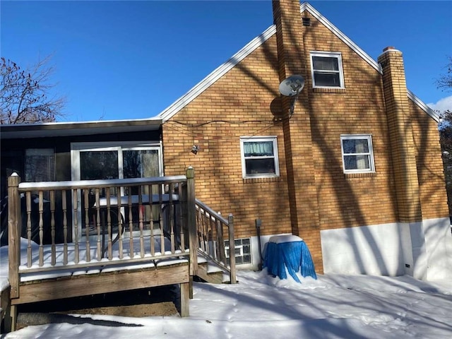 snow covered back of property featuring a wooden deck