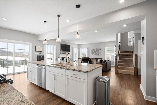 kitchen featuring dishwasher, a center island with sink, light stone counters, sink, and white cabinetry