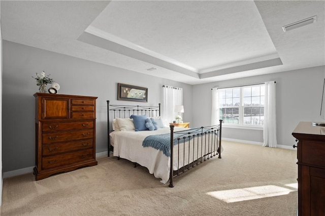 bedroom with a raised ceiling and light colored carpet