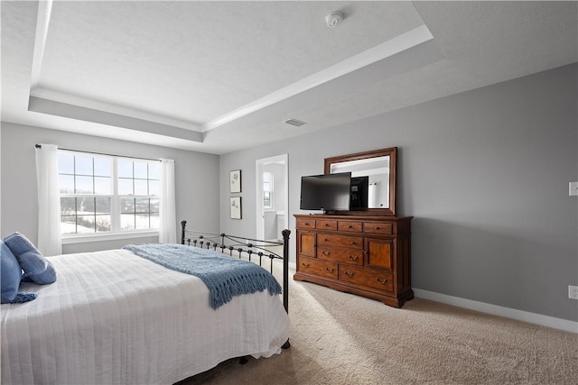 carpeted bedroom with ensuite bath and a tray ceiling