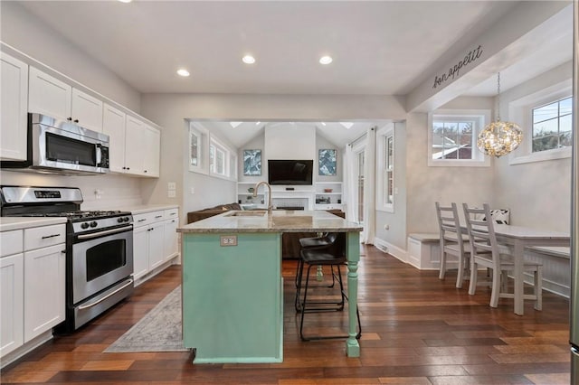 kitchen with a kitchen breakfast bar, white cabinetry, a center island with sink, and appliances with stainless steel finishes