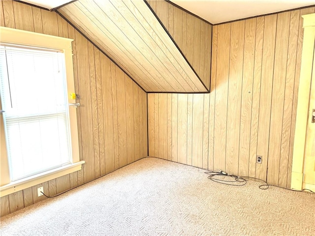 additional living space with wooden walls, light colored carpet, and lofted ceiling