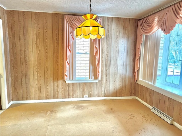 spare room with wood walls, crown molding, and a baseboard heating unit