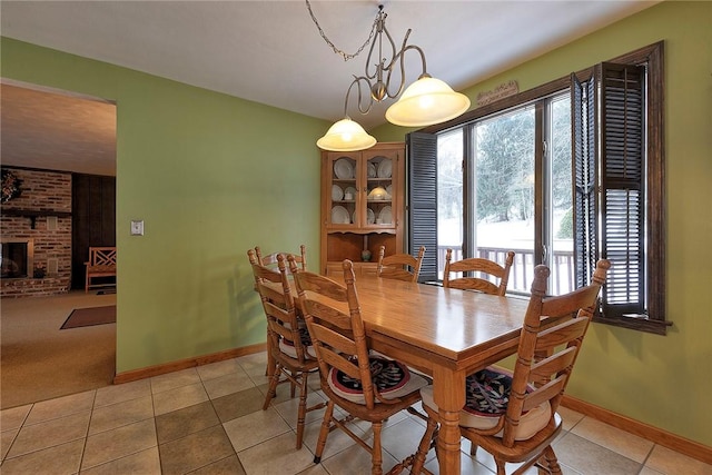 dining space featuring light tile patterned floors and a brick fireplace