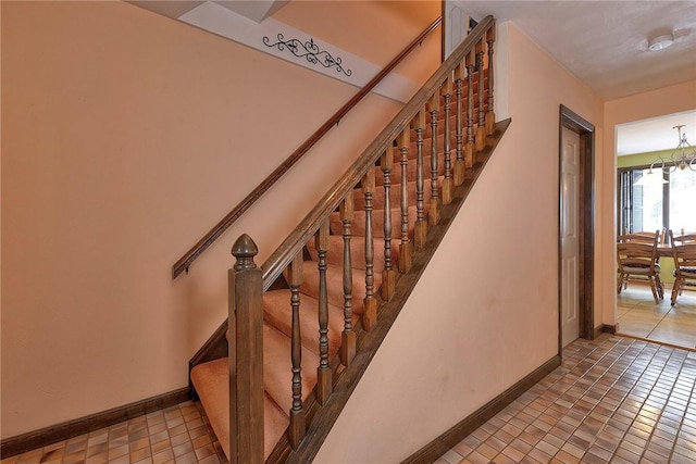 stairway with tile patterned floors and a notable chandelier