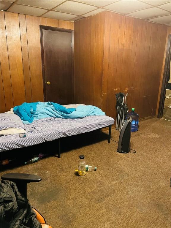 bedroom with carpet floors and wood walls