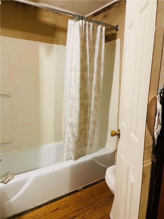 bathroom featuring toilet, wood-type flooring, and shower / tub combo