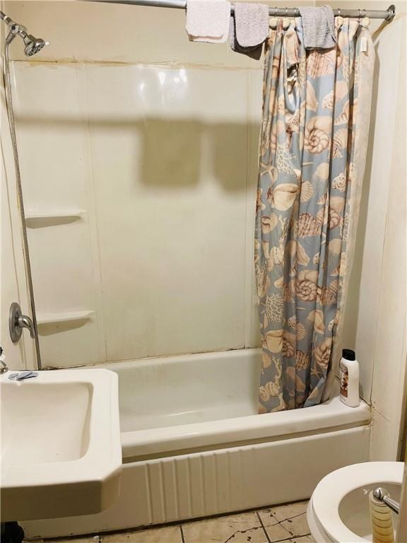 bathroom featuring tile patterned floors, shower / bath combination with curtain, and toilet