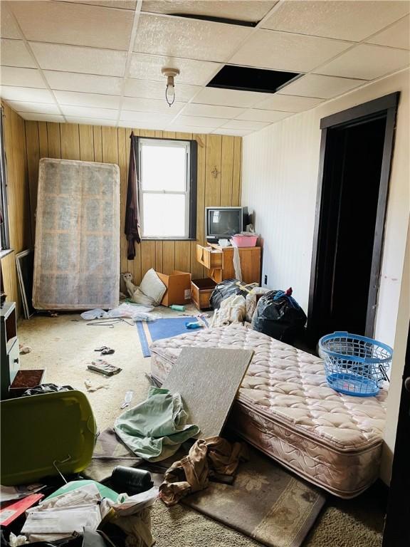 miscellaneous room featuring a drop ceiling and wooden walls